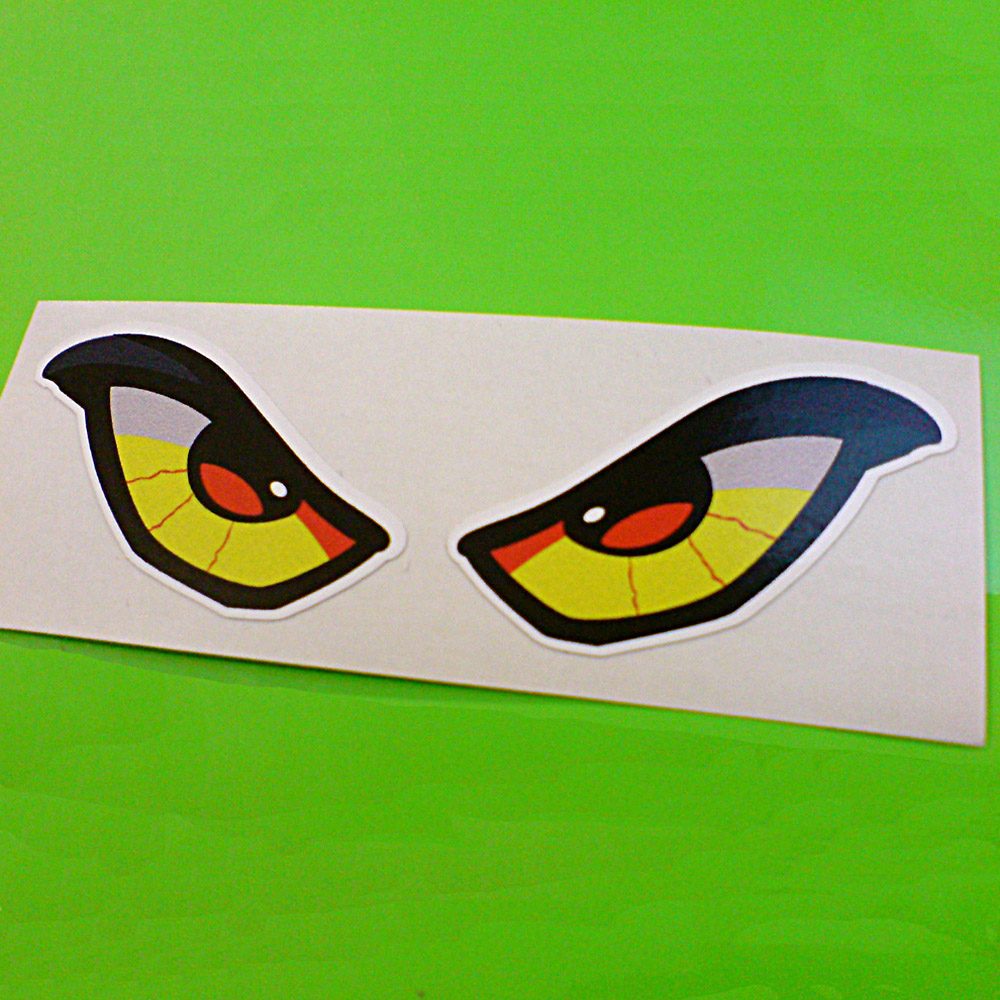 ALIEN EYES STICKER. A pair of alien eyes outlined in thick black. The pupil is red, the iris is black, the area around is yellow with red threadlike veins.