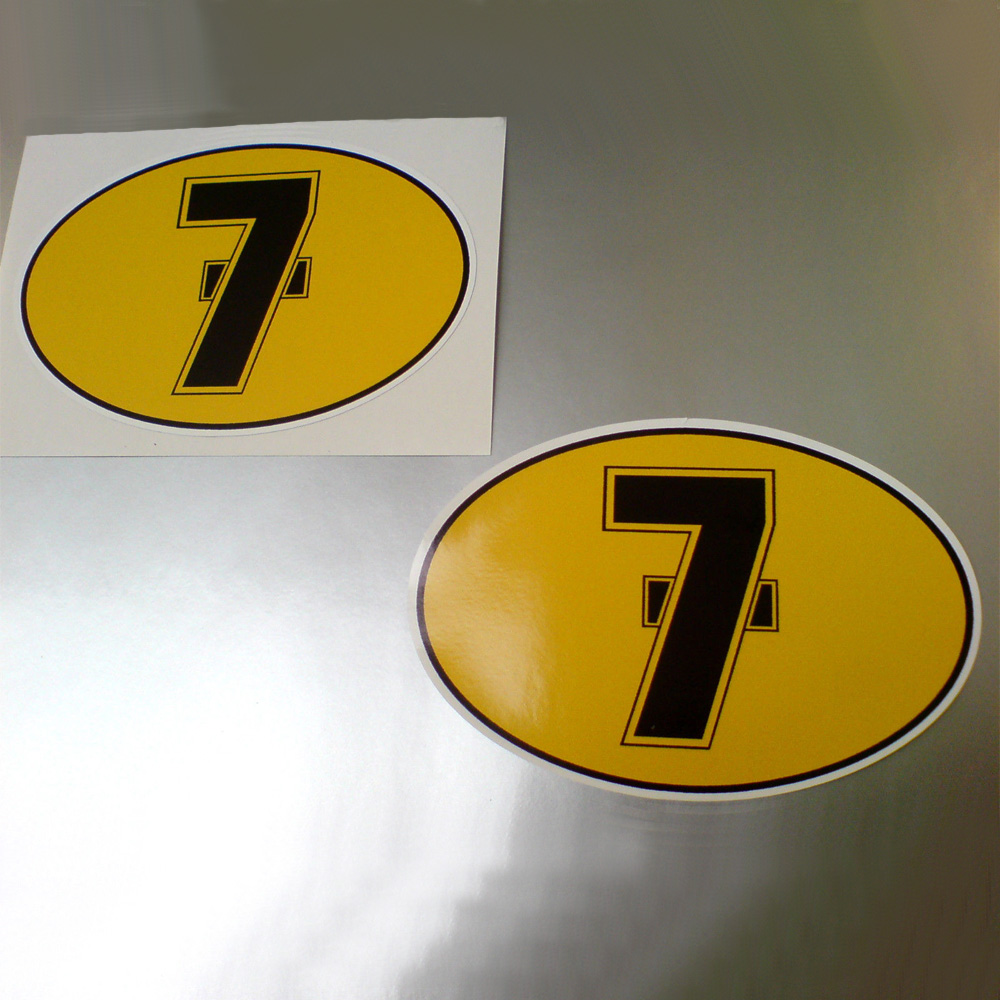 A black number 7 with a line in the middle on a yellow oval sticker with a black border.