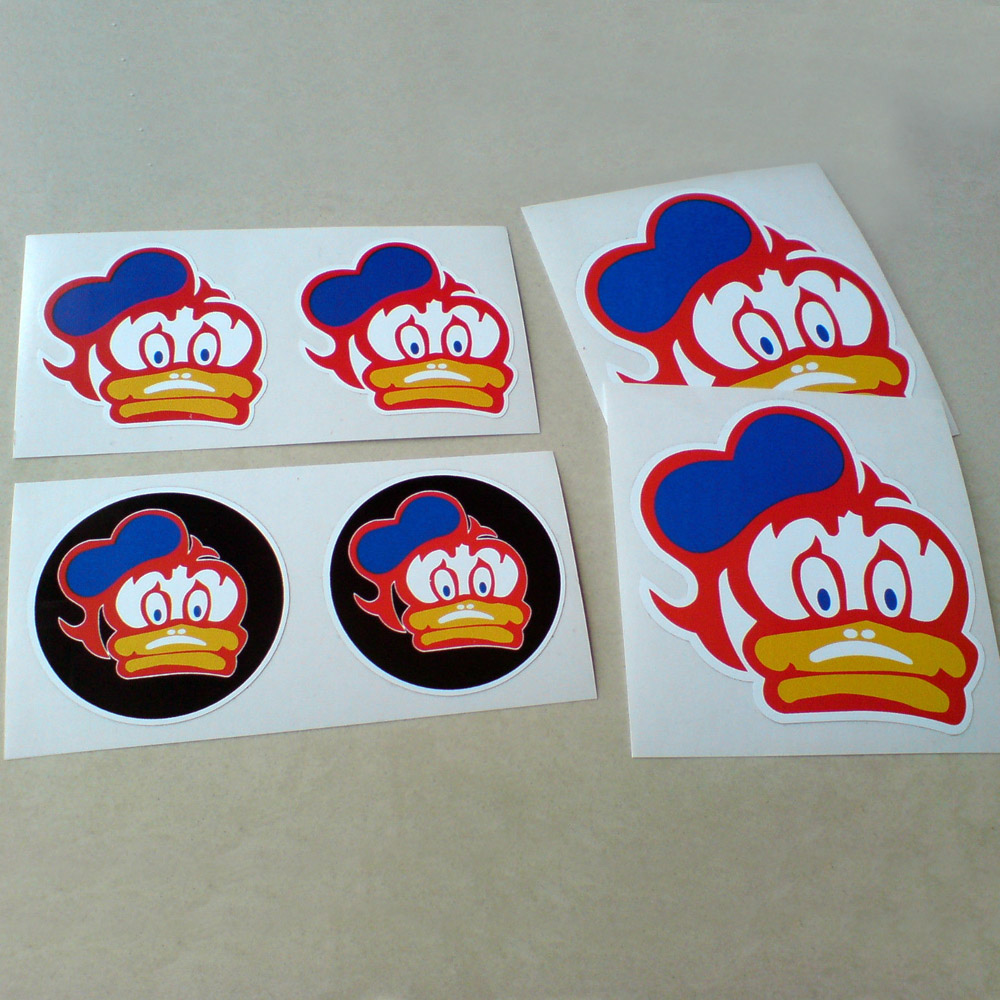 BARRY SHEENE DUCK STICKERS SET. A duck with a white face and a yellow bill wearing a blue sailor cap, all outlined in red. Also, the same design on a black circle.