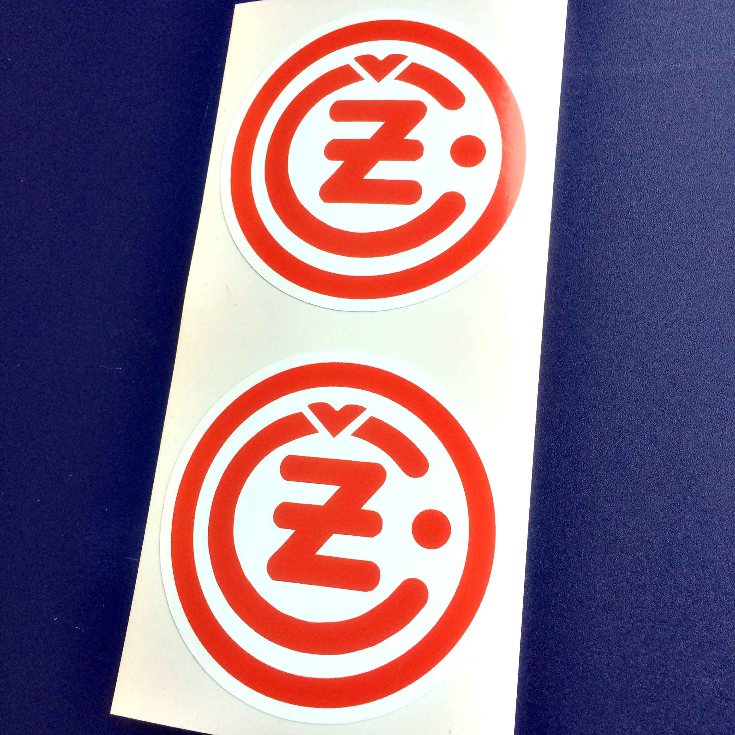 CZ MOTORCYCLE STICKERS. Two concentric circles in red. The area around them is white. The inner circle is shaped in a C with a Z in the centre. Above the Z is a v shape. To the right of the Z is a dot also in red.