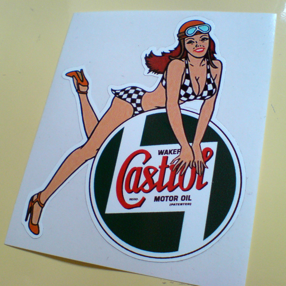 A long auburn haired model wearing a black and white chequered bikini, heels and a helmet and goggles on her head. She is leaning on a circular classic Castrol logo; green with Castrol in red lettering.