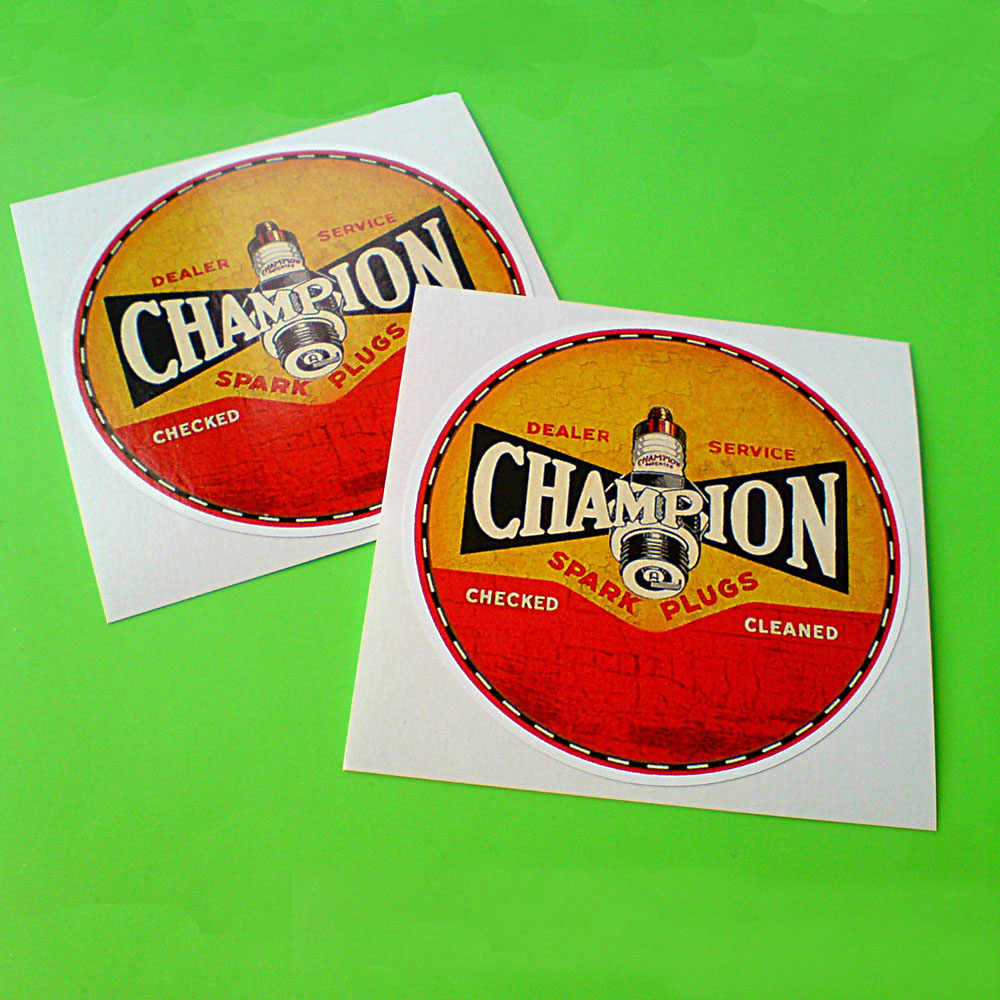A vintage looking circular sticker half red half yellow with a black and white edge. Champion in white uppercase lettering on a black background with a spark plug in the centre. Additional text in red and white; Dealer Service Spark Plugs Checked Cleaned.