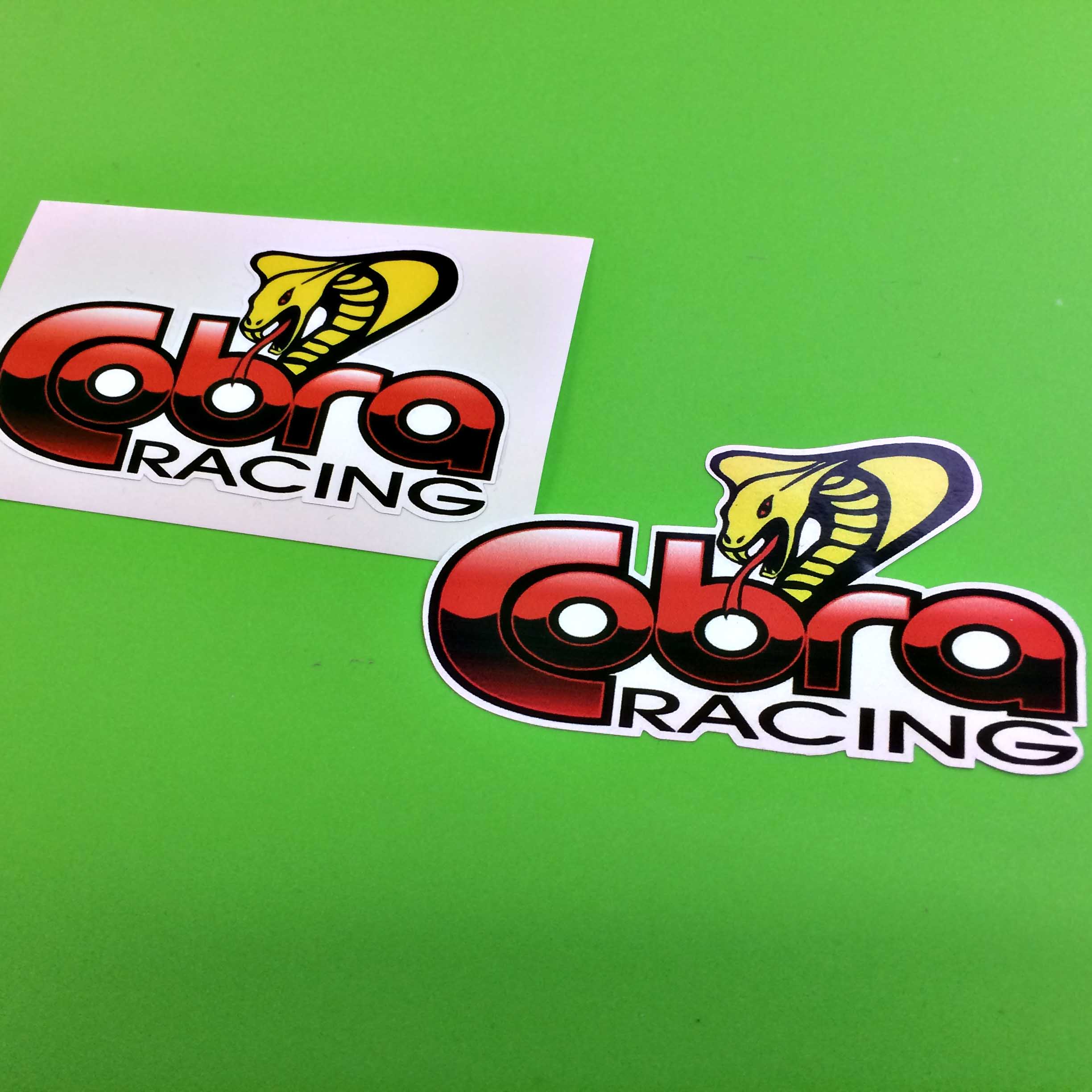 COBRA RACING STICKERS. Cobra in bold red lettering, Racing in black lettering below. A yellow cobra with a red tongue sits between b and r in Cobra.