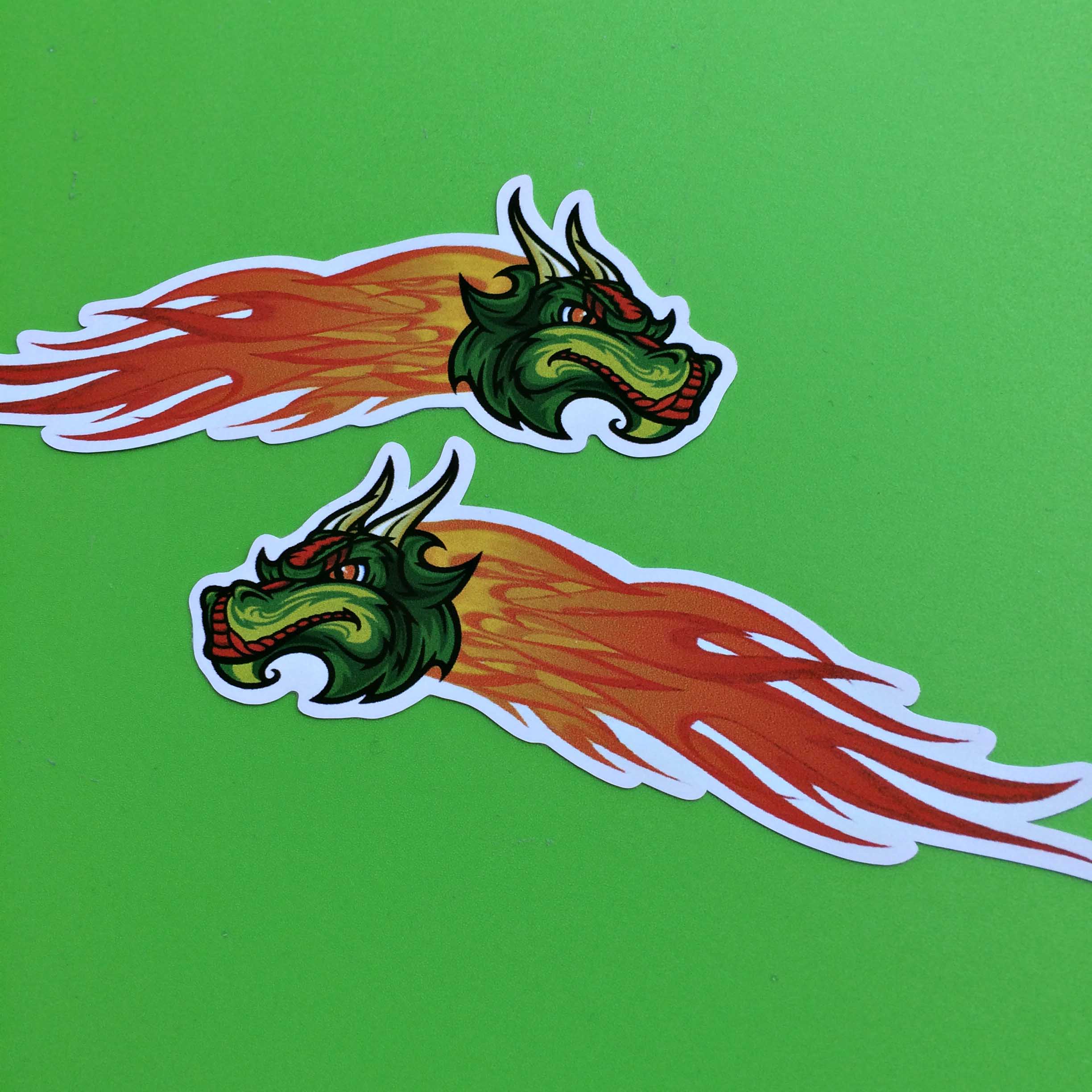 A head of a dragon, green with horns and piercing red eyes. Orange and red flames are trailing behind.