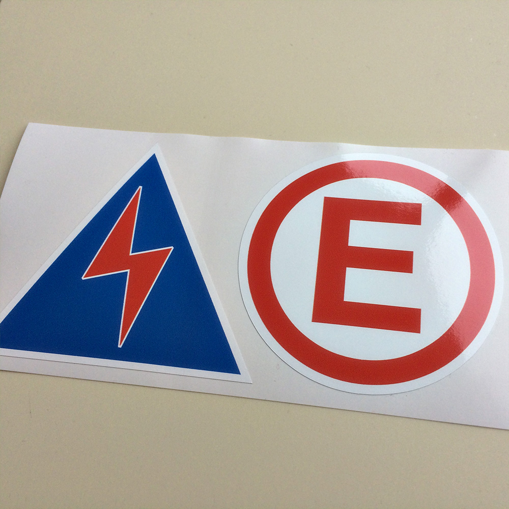 ELECTRICAL CUT OFF AND FIRE EXTINGUISHER STICKER. Blue triangle with a red lightning bolt in the centre. Also a white circle with a band of red around the circumference. Centre is a capital E in red.