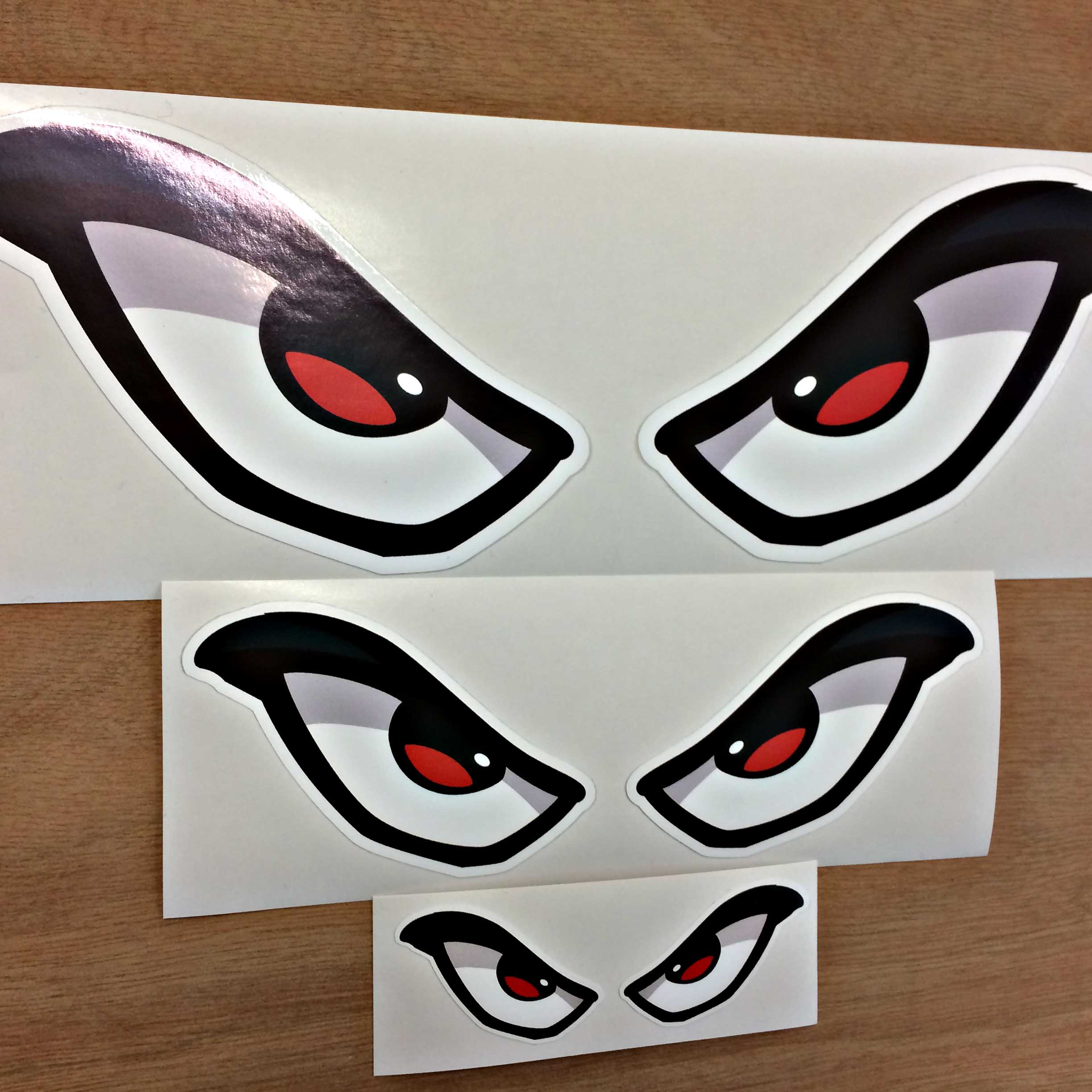 EVIL EYES STICKER. A pair of white evil eyes with red pupils outlined in thick black.