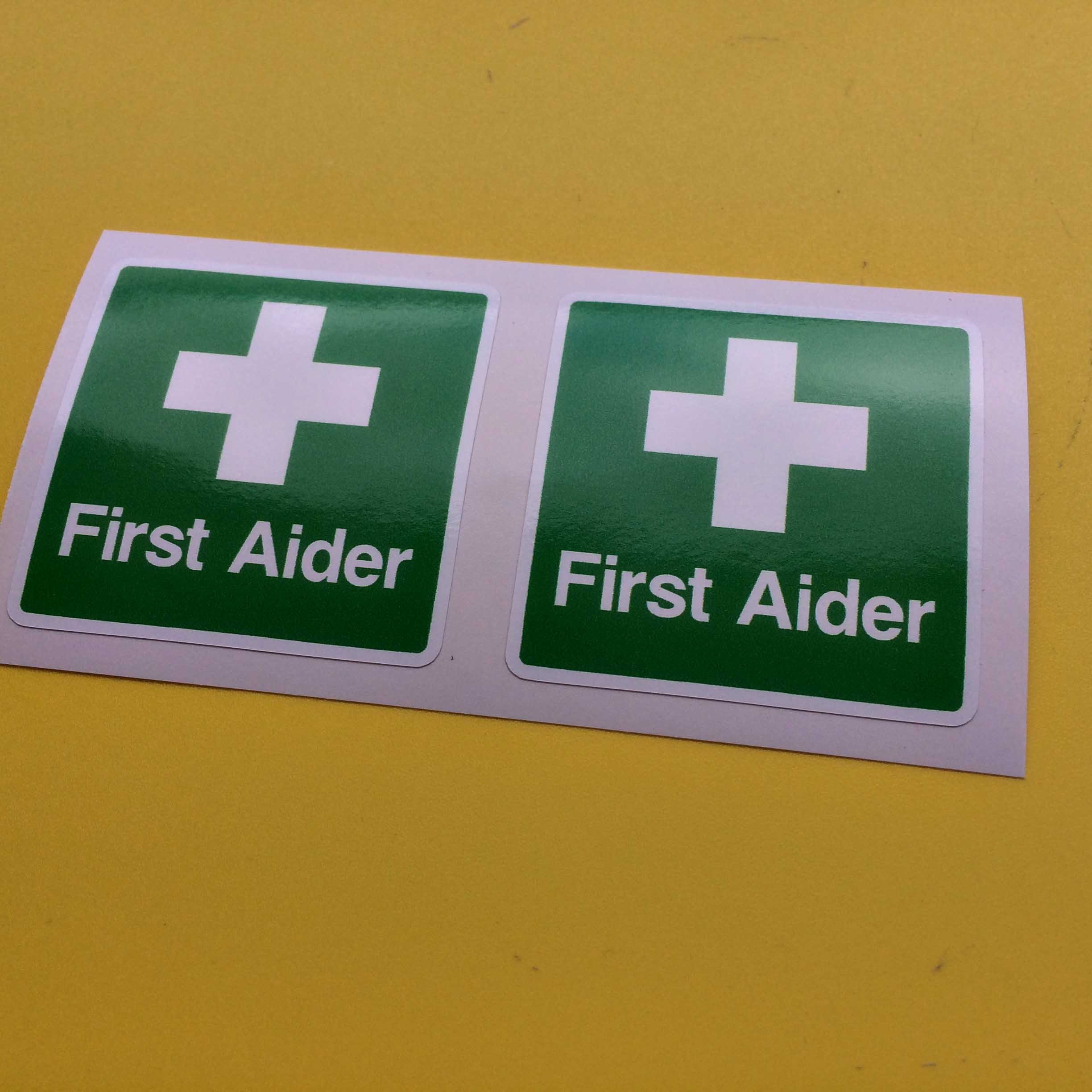FIRST AIDER STICKERS. First Aider in white letters and a white cross on a green square.