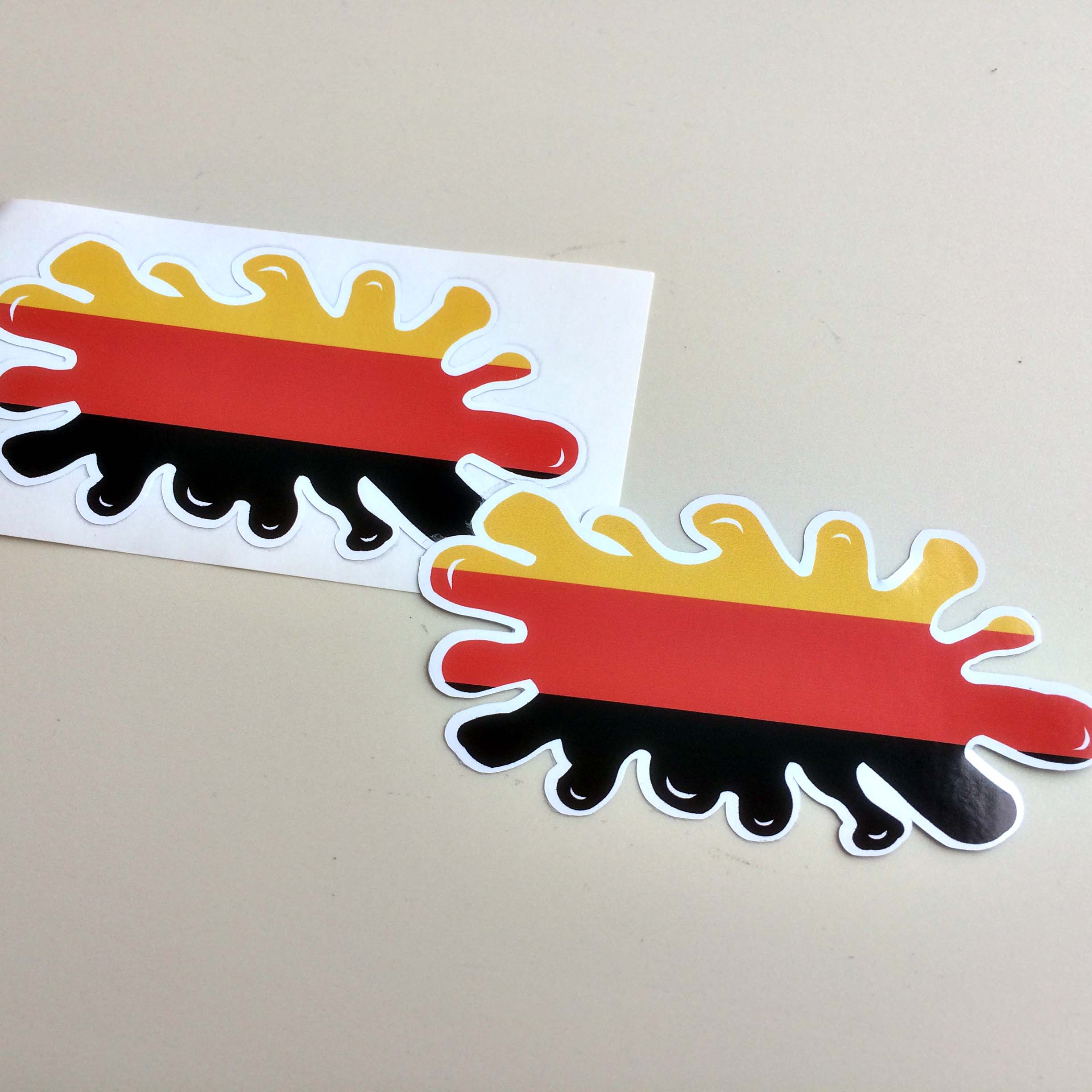 GERMAN GERMANY FLAG SPLAT STICKERS. The German flag. A tricolour of gold, red and black horizontal stripes in the shape of a paint splat.