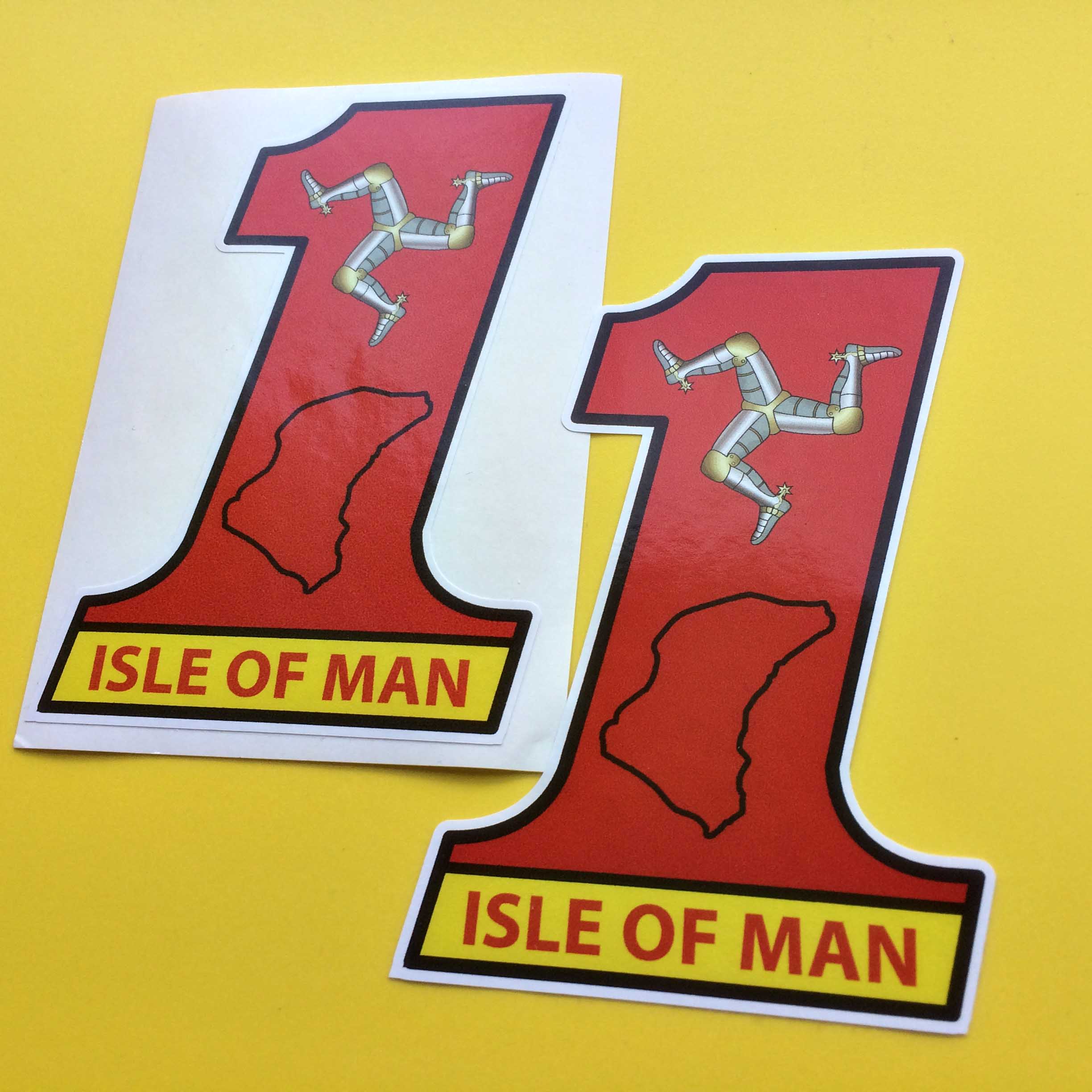 ISLE OF MAN NO 1 TT STICKERS. Isle of Man in red lettering on a yellow background at the base of a number 1 in red. Additional images of the Manx triskelion in silver and gold and a contour in black of the Isle of Man.