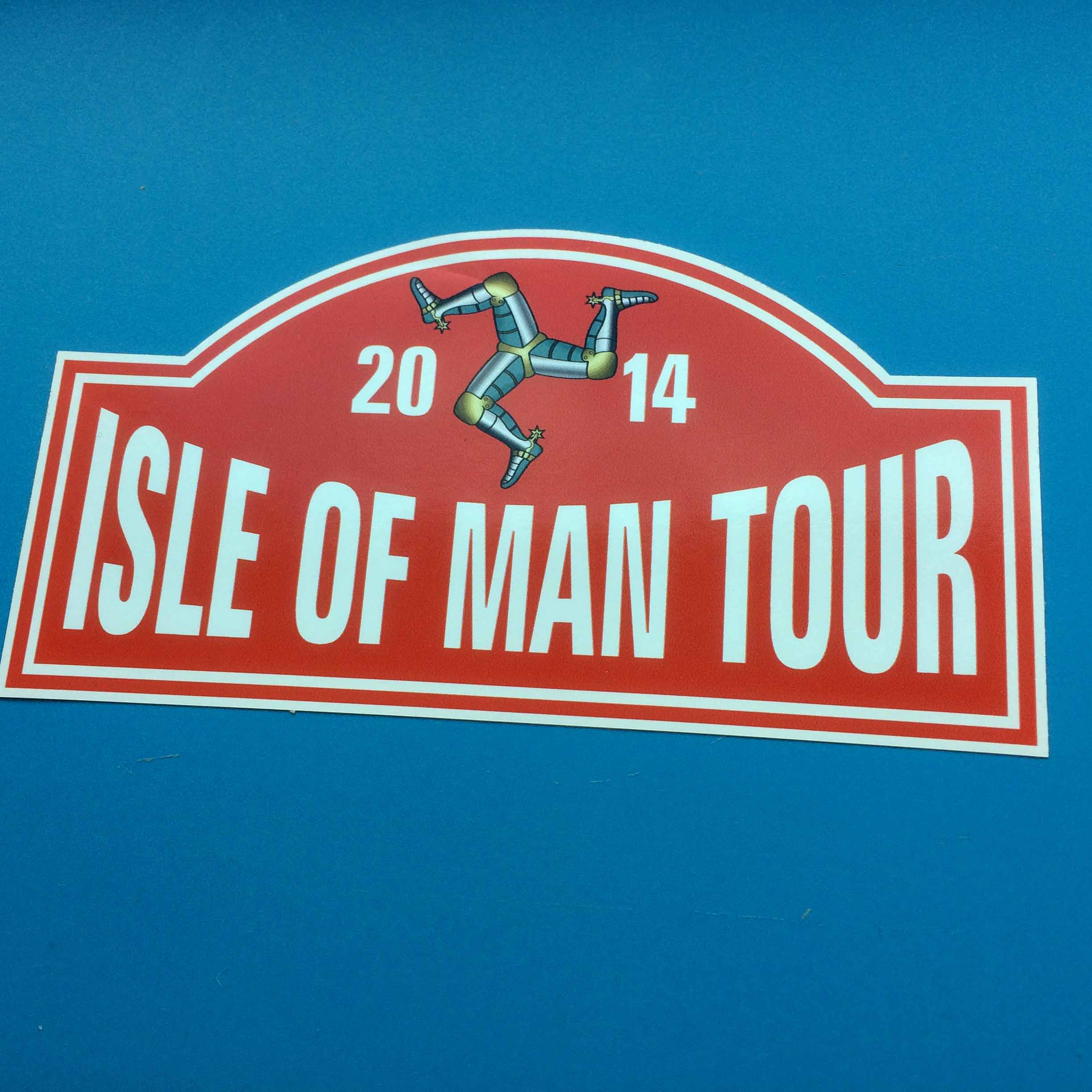 Isle Of Man Tour 2014 in bold white lettering on a red background. Above is the Isle Of Man triskelion.