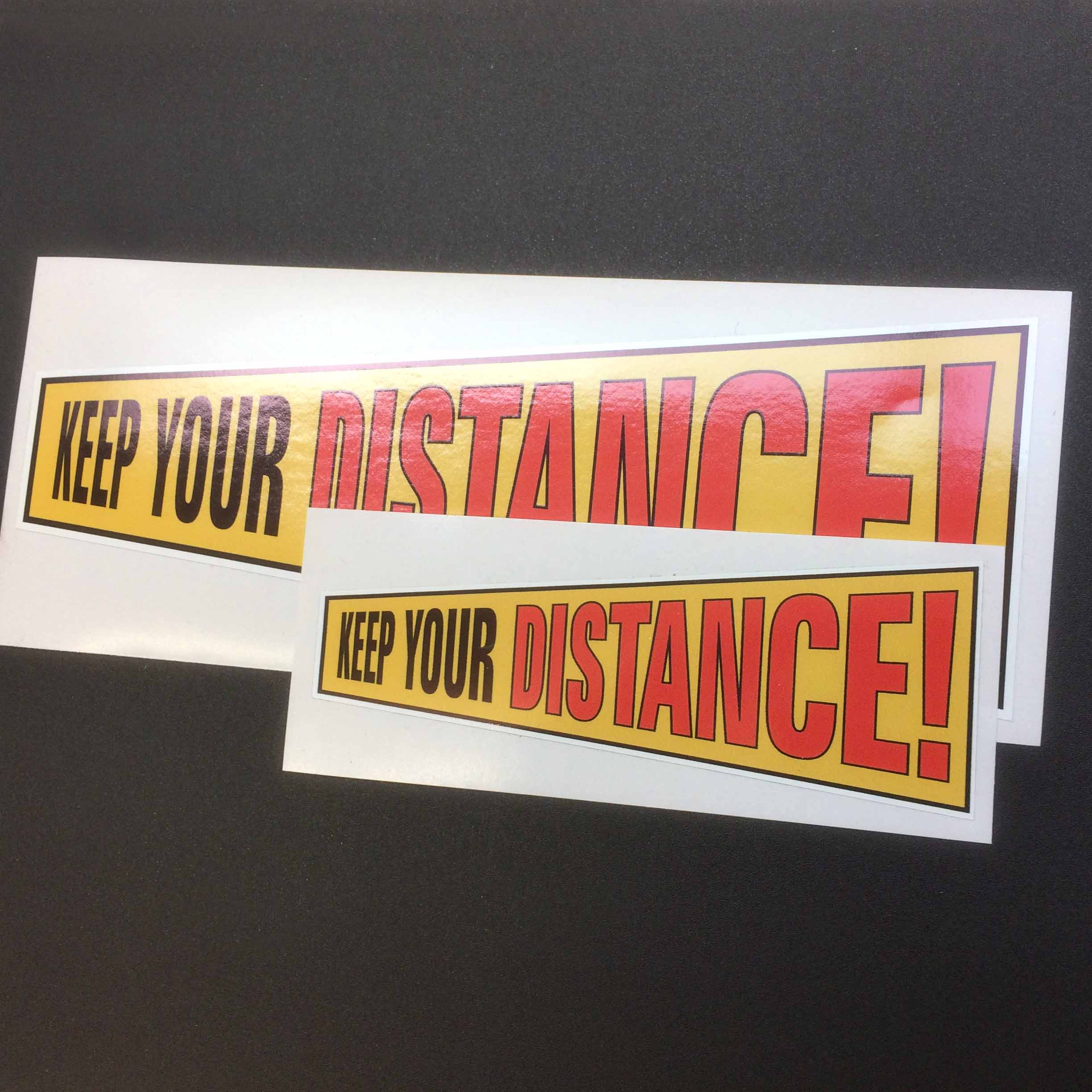 KEEP YOUR DISTANCE STICKER - 2 SIZES AVAILABLE. Keep Your in black lettering. Distance! in red lettering. On a yellow background.