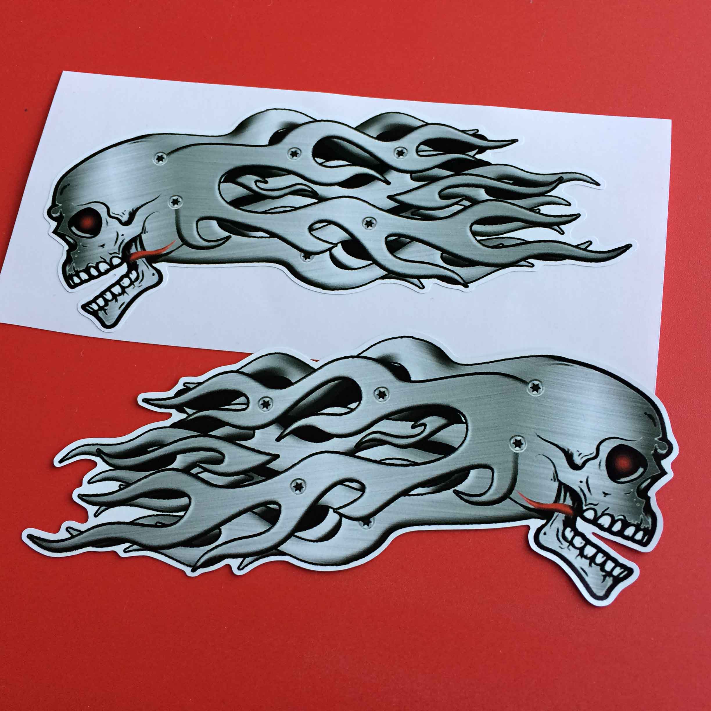 MAD SKULL AND FLAMES STICKERS. Side view of a metal skull with white teeth and red eye socket and tongue. Metal flames are flowing behind.
