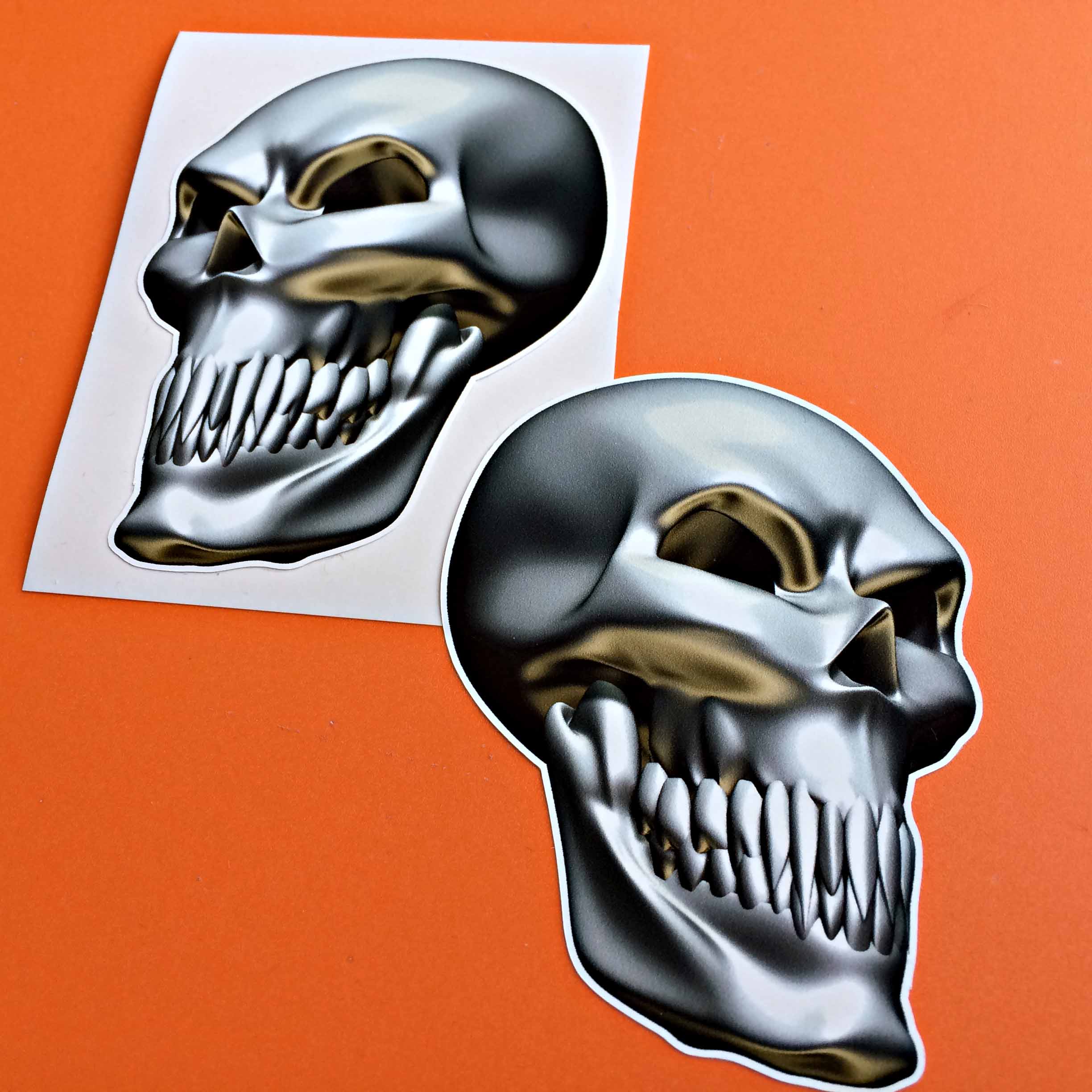 METAL SKULL STICKERS. Partial side view of a metal skull with teeth. The eye socket and cheekbone area is gold.