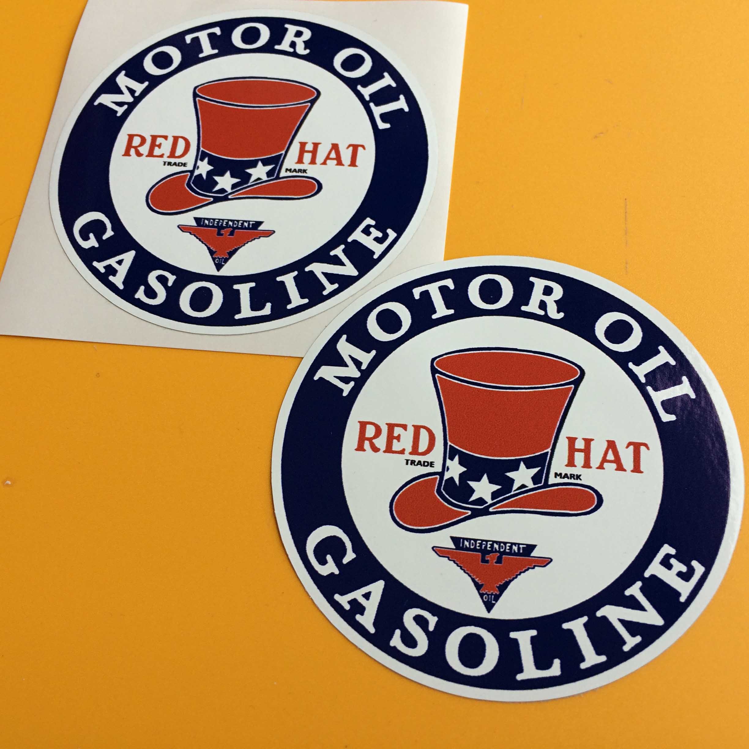 Red Hat Motor Oil Gasoline surrounds a patriotic top hat inside two concentric circles of blue and white. Below the hat is a red eagle and Independent Oil on a blue flipped triangle.