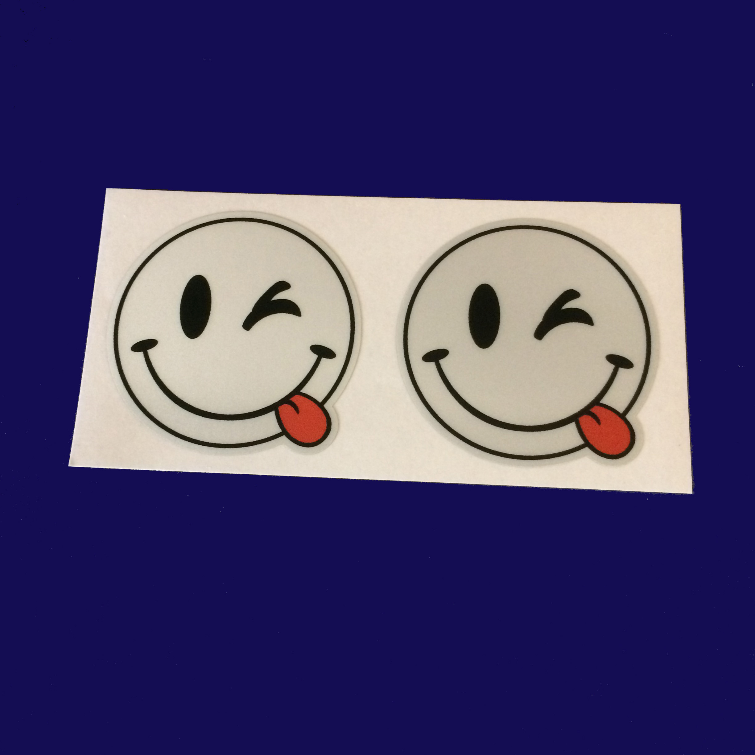 REFLECTIVE CHEEKY SMILEY EMOJI STICKERS. A smiling face winking an eye and sticking out a red tongue.