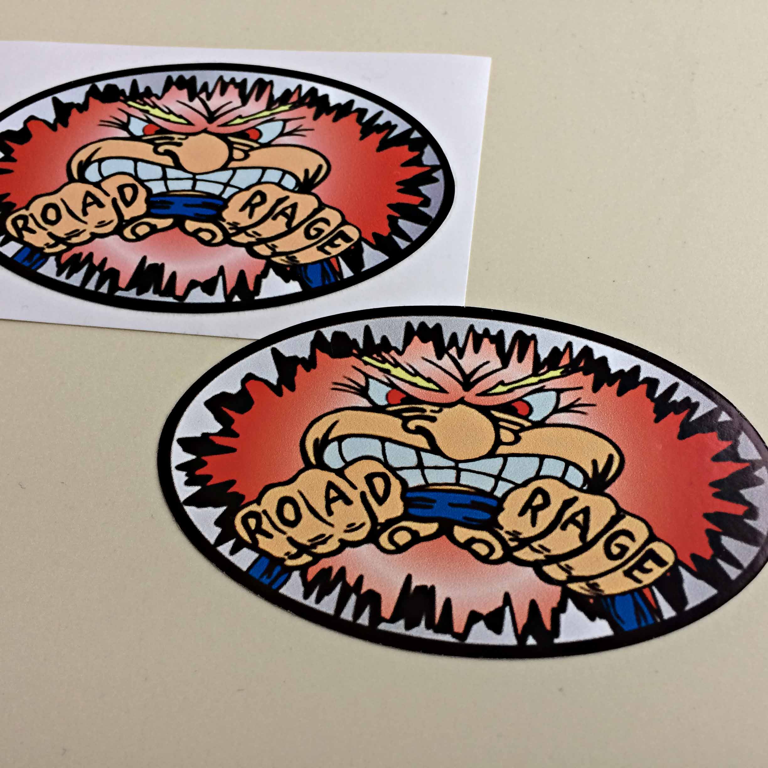 ROAD RAGE STICKERS. Road Rage is tattooed on the fingers of a man gripping a steering wheel. A humorous character. He has fuzzy red hair, red eyes and baring white teeth in anger.