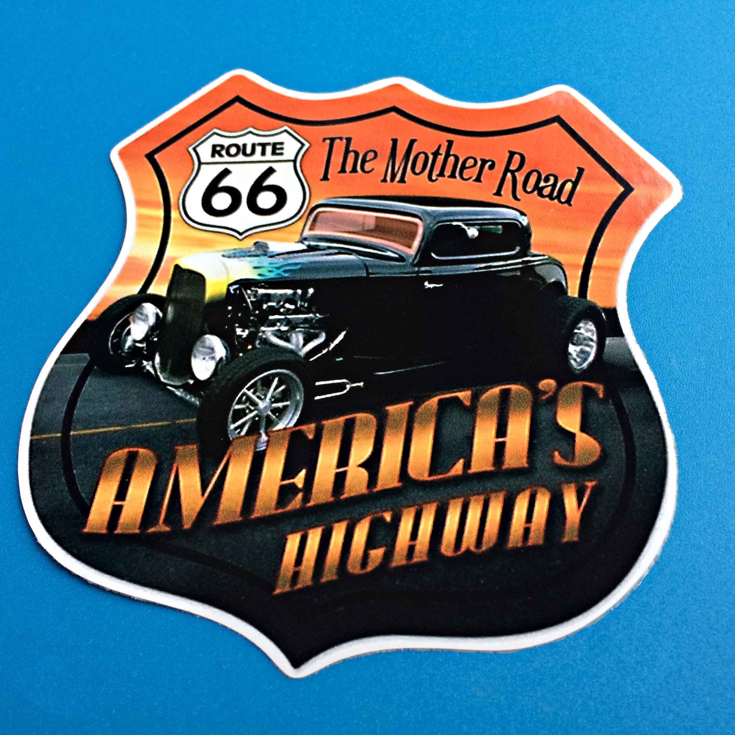 ROUTE 66 AMERICAS HIGHWAY STICKER. Route 66 sign, The Mother Road America's Highway lettering in gold. An American black classic car on the highway at sunset . A Route 66 sign shaped sticker.