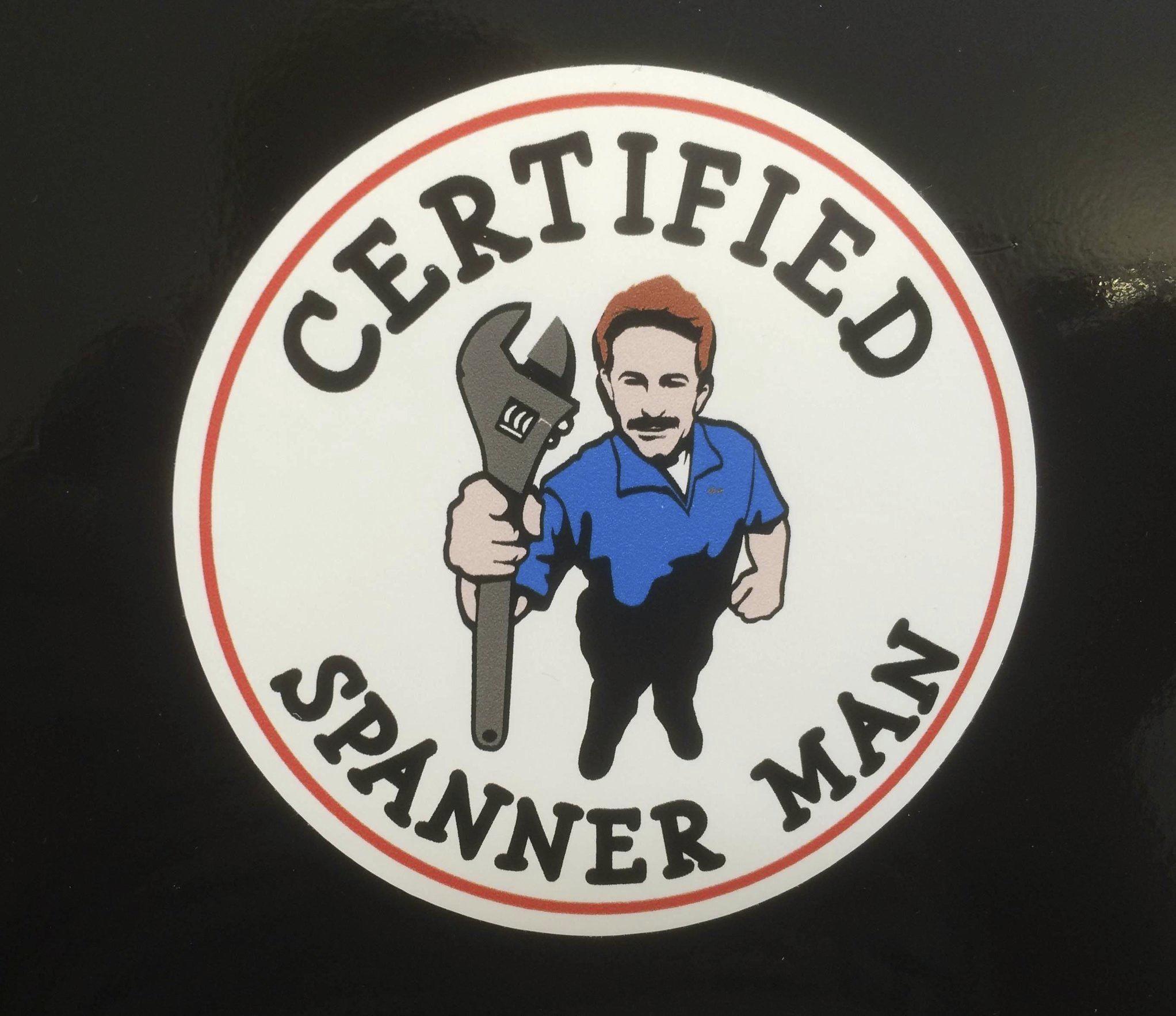 CERTIFIED SPANNER MAN STICKER. Certified Spanner Man in black lettering surrounds a man dressed in blue overalls holding a spanner. A white circular sticker with a red border.