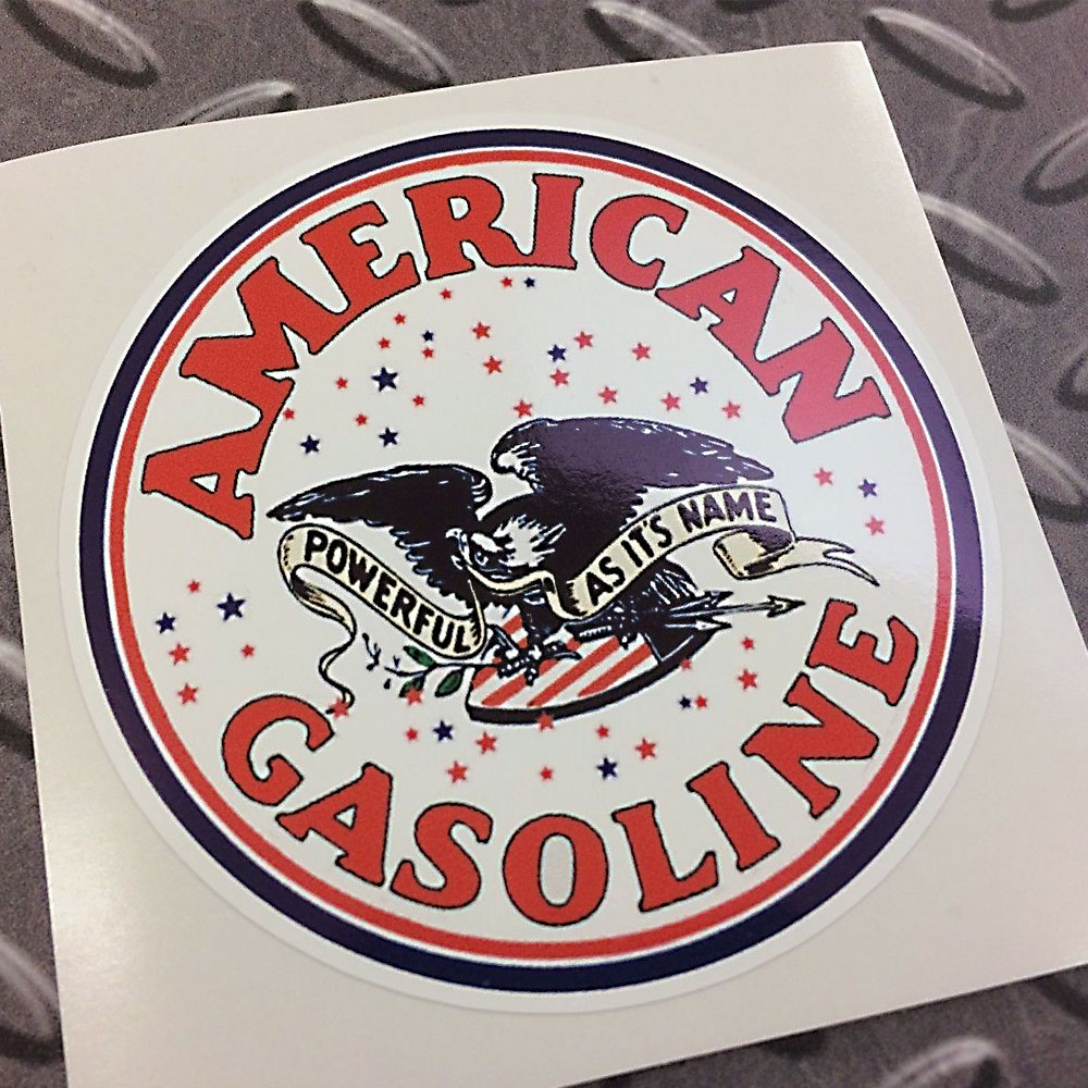 AMERICAN GASOLINE STICKER. American Gasoline in red lettering surrounds a white circular sticker with a black and red border. In the centre is a black eagle with a banner between it's beak, Powerful As It's Name. Red and black stars surround it.