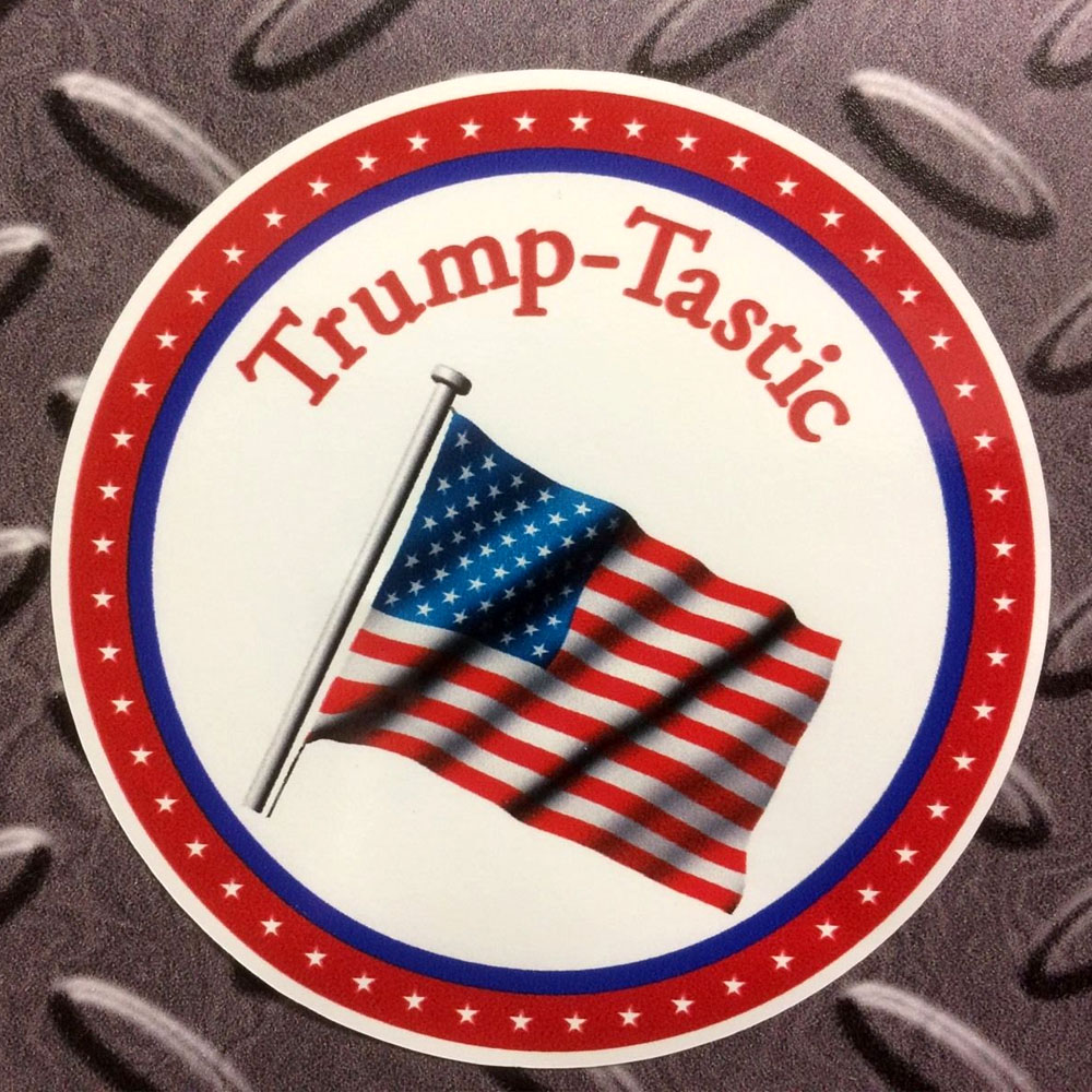 TRUMP-TASTIC PRESIDENT STICKER. Three concentric circles. Trump-Tastic in red lettering and the Star and Stripes flying on a flagpole on a white circle. A blue circle and a red circle with white stars surrounds this.