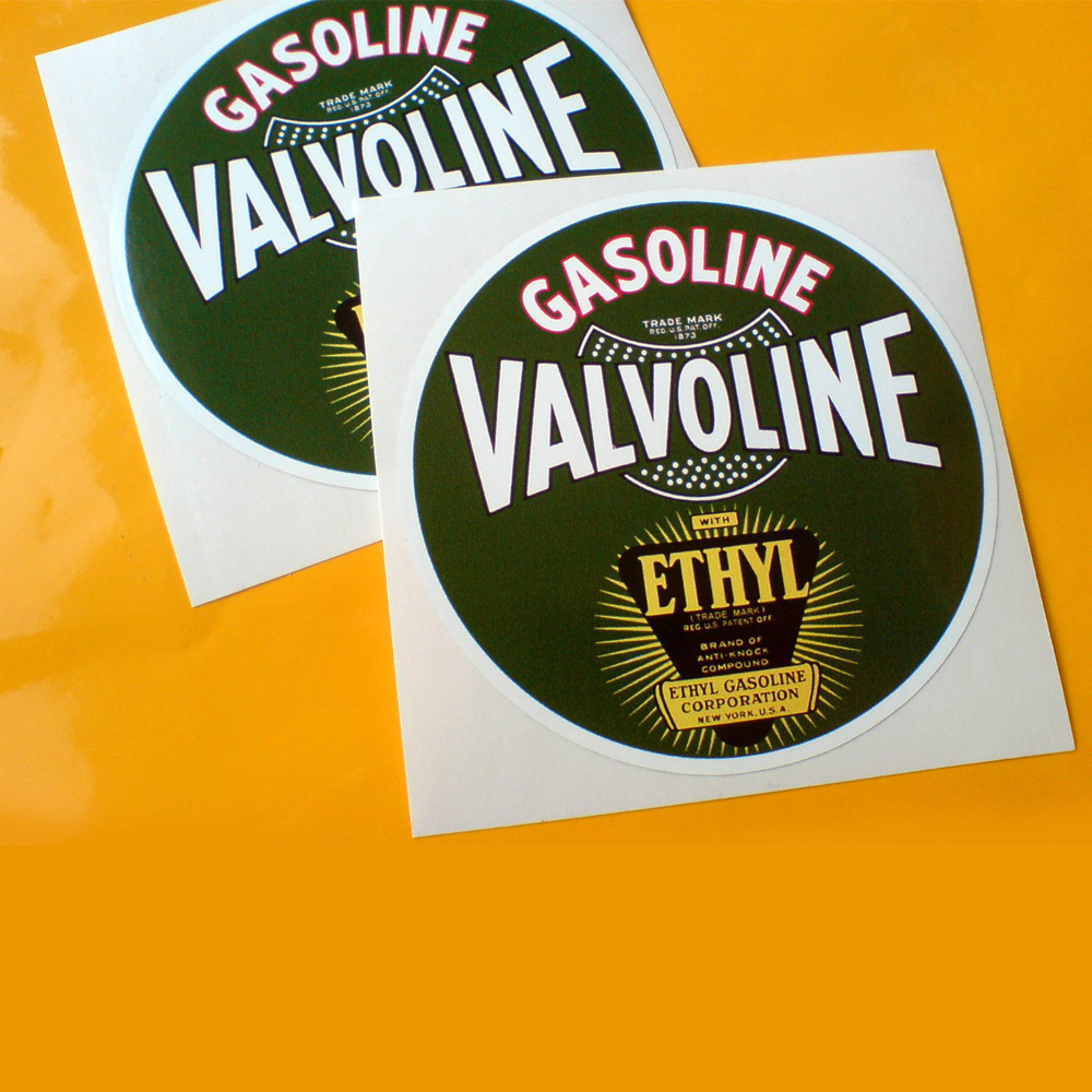 A green circular sticker. Gasoline in white lettering with a red border. Valvoline in white bordered in black. Ethyl in yellow lettering sits on an inverted triangle in black surrounded by sunrays.