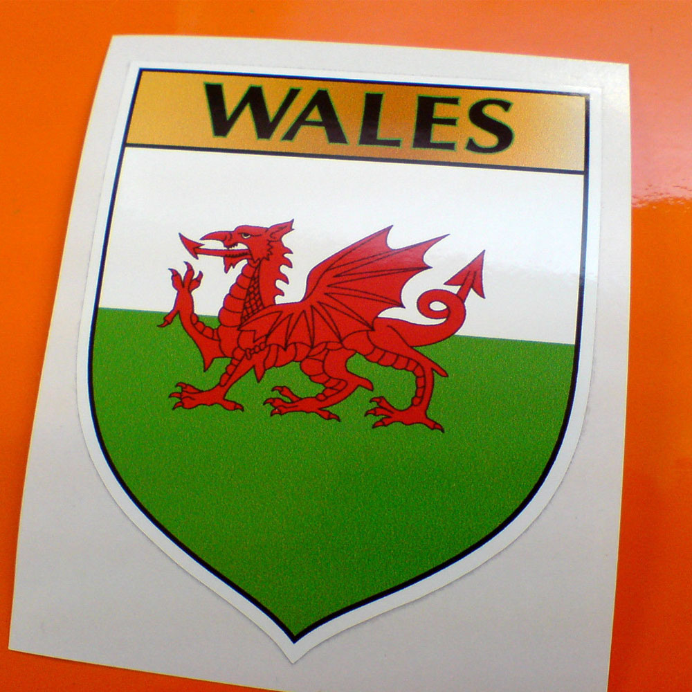 WALES / WELSH SHIELD STICKER A red dragon on a green and white field. Wales in black lettering on a gold banner across the top of the shield.