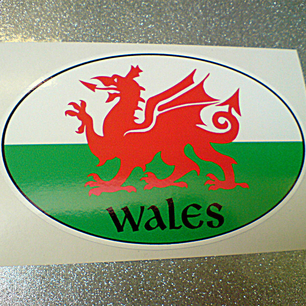 WALES/WELSH FLAG OVAL STICKER. A red dragon on a green and white field. Wales in black lettering.