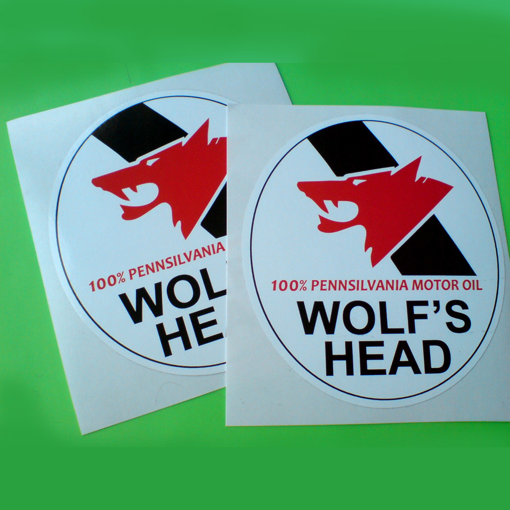 WOLFS HEAD MOTOR OIL STICKERS. A red wolf's head on a black diagonal banner. Below in red lettering 100% Pennsylvania Motor Oil and Wolf's Head in bold black uppercase lettering on a white circular sticker.