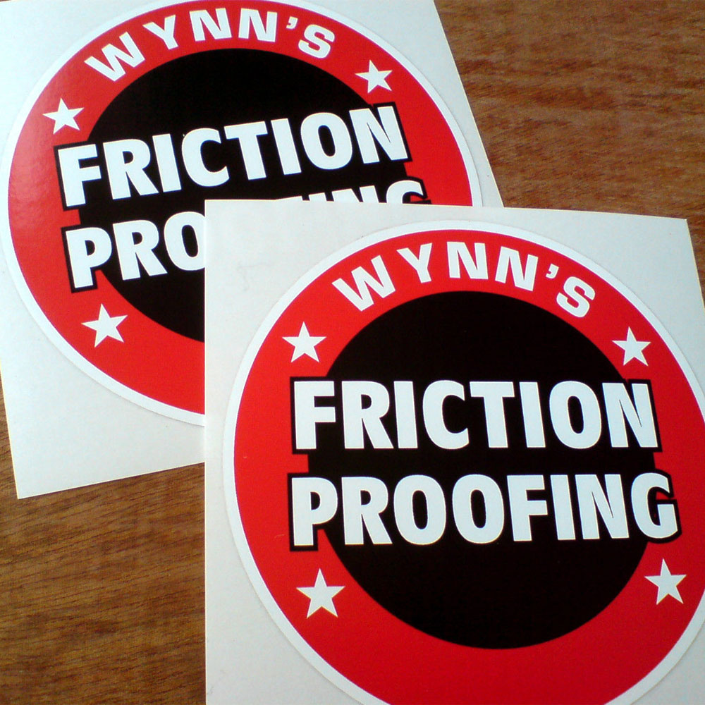 WYNNS FRICTION PROOFING STICKERS. Two concentric circles in red and black. Wynn's and four stars in white surround the red outer circle. Friction Proofing in white uppercase lettering is across the centre.