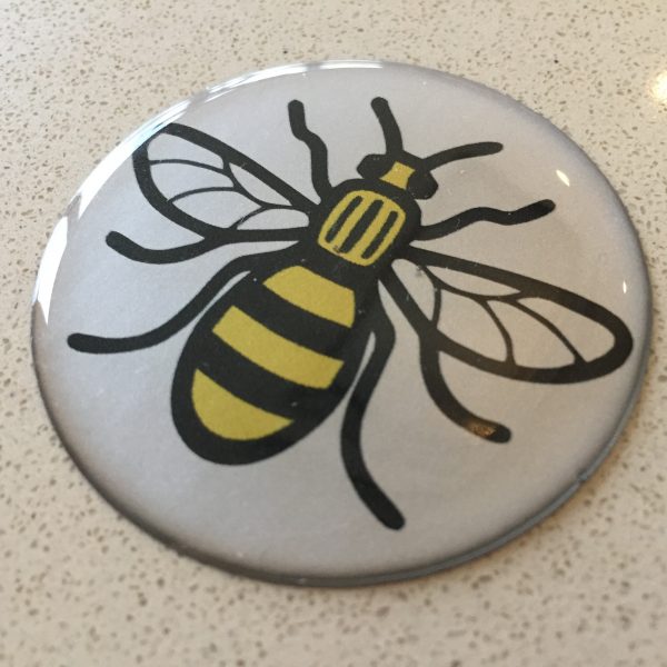 Black and yellow bee on a round, domed sticker.
