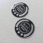 Black Edition, stars and laurel leaf design in silver on a black circular sticker.