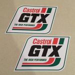 Parallelogram stickers. Castrol red lettering at the top. GTX bold, black uppercase lettering in the centre. The High Performer in green lettering below. Two red and green bands of colour around two sides. White background.