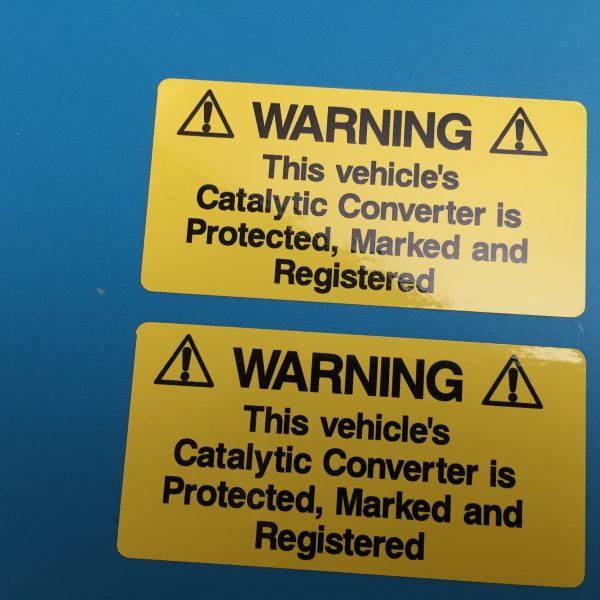 WARNING! CATALYTIC CONVERTER STICKERS. Catalytic Convertor Warning Stickers. Black text on either a yellow, white or silver background. With the word Warning in bold capital letters. The rest of the text 'This vehicle's Catalytic Converter is Protected, Marked and Registered' in lower case.