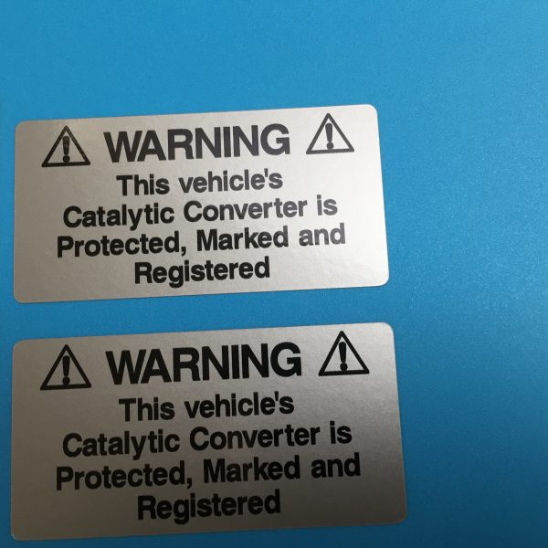 WARNING! CATALYTIC CONVERTER STICKERS. Catalytic Convertor Warning Stickers. Black text on either a yellow, white or silver background. With the word Warning in bold capital letters. The rest of the text 'This vehicle's Catalytic Converter is Protected, Marked and Registered' in lower case.