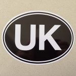 UK OVAL STICKER FOR CARS VANS AND TRUCKS - LEGAL SIZE 18CMS X 11.5CMS. UK in bold white lettering on a black background.