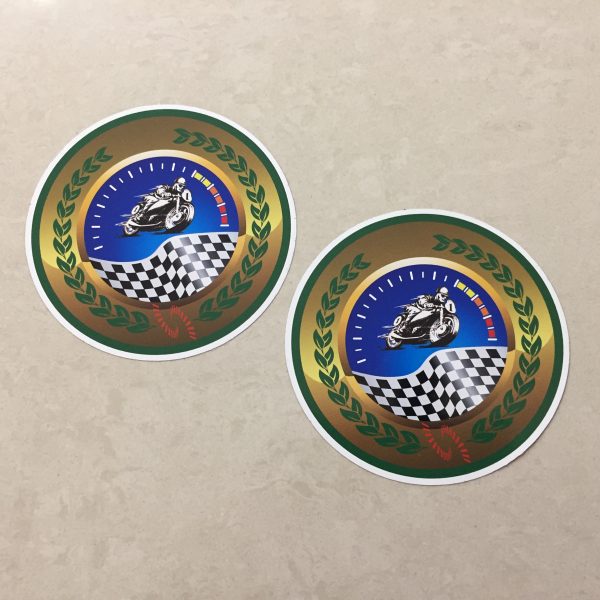 MOTORCYCLE SPEEDWAY RACING STICKERS. A man racing a motorcycle on a speedway and a chequered flag overlays a speedometer. A green laurel leaf on a gold background surrounds the image.