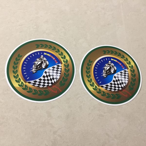 MOTORCYCLE SPEEDWAY RACING STICKERS. A man racing a motorcycle on a speedway and a chequered flag overlays a speedometer. A green laurel leaf on a gold background surrounds the image.