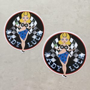 LADY LUCK STICKERS. Lady Luck in silver lettering on a black background. A blonde pin up wearing a number 8 bikini top and four aces sarong with a horseshoe in her hair. She stands in front of crossed chequered flags while holding a tool and a clover leaf.