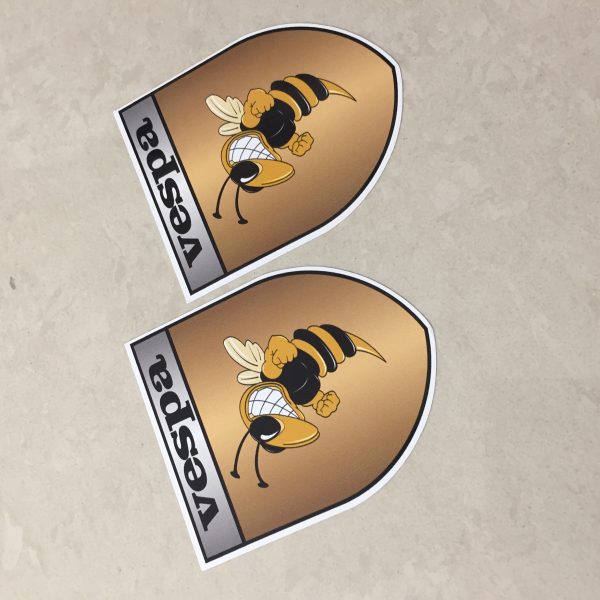 VESPA GOLD STICKERS. Vespa in black lettering on a silver banner at the top of the gold shield. A wasp displaying antennae, wings and white teeth is clenching its fists.