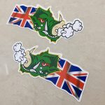 UNION JACK WARTHOG STICKERS. A green headed warthog with red eyes and white horns. Air is expelling from the nostrils. A Union Jack flag is flowing behind.