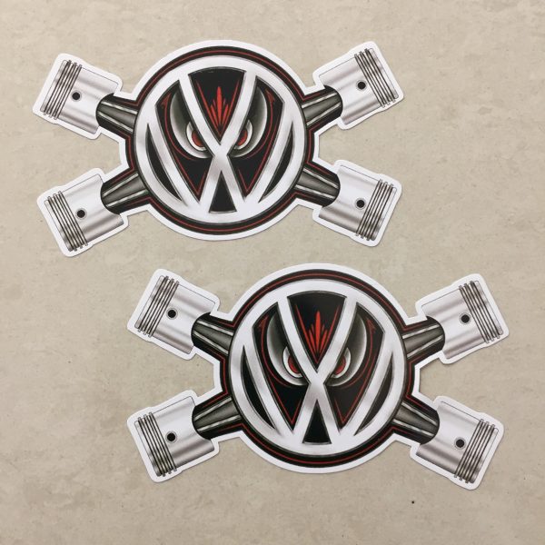 VW PISTON EYES STICKERS. The VW logo overlays two crossed pistons. A pair of red evil eyes peer from behind the logo.