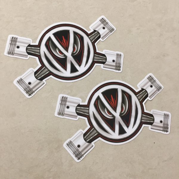 VW PISTON EYES STICKERS. The VW logo overlays two crossed pistons. A pair of red evil eyes peer from behind the logo.
