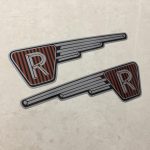 RALEIGH RUNABOUT FAIRING STICKERS. The letter R in silver on a black and brown vertical striped background inside an inverted triangle. A silver wing effect protrudes from one side.