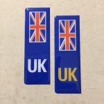 NUMBER PLATE ORIGIN STICKERS DOMED RESIN GEL UK. Two blue columns. UK in white at the base of one column. UK in yellow on the other. Both stickers have the Union Jack at the top.