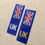NUMBER PLATE ORIGIN STICKERS DOMED RESIN GEL UK. Two blue columns. UK in white at the base of one column. UK in yellow on the other. Both stickers have the Union Jack at the top.