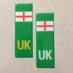 NUMBER PLATE ORIGIN EV STICKERS DOMED RESIN GEL ENGLAND. Two green columns. UK in white at the base of one column. UK in yellow on the other. Both stickers have the England flag at the top.