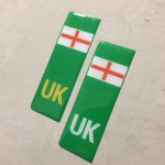 NUMBER PLATE ORIGIN EV STICKERS DOMED RESIN GEL ENGLAND. Two green columns. UK in white at the base of one column. UK in yellow on the other. Both stickers have the England flag at the top.