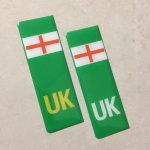 NUMBER PLATE ORIGIN EV STICKERS DOMED RESIN GEL ENGLAND. Two green columns. UK in white at the base of one column. UK in yellow on the other. Both stickers have the England flag at the top.