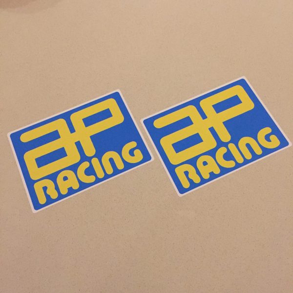 AP RACING STICKERS. AP Racing in bold yellow uppercase lettering on a blue rectangular sticker.