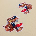 ANGRY DOG STICKERS. A cartoon character of an angry dog with a brown coat, a big nose, floppy ears and yellow eyes. The jaws are wide open displaying sharp white teeth and a red tongue.
